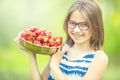 Cute little girl with bowl full of fresh strawberries. Pre - teen girl with glasses and teeth - dental braces Royalty Free Stock Photo