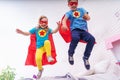 Cute little girl and boy jumping from bed to fly, play superhero Royalty Free Stock Photo