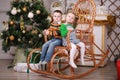 Cute little girl and boy sitting in rocking chair near christmas tree Royalty Free Stock Photo