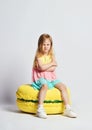 Cute little girl in bright clothes have fun at the birthday party fun room decoration candy macarons