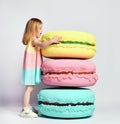 Cute little girl in bright clothes have fun at the birthday party fun room decoration candy macarons