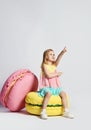 Cute little girl in bright clothes have fun at the birthday party fun room decoration candy macarons