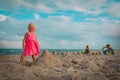 Cute little girl with brother and sister play with sand building castle on beach Royalty Free Stock Photo
