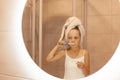 Cute little girl brushing teeth in bathroom while standing in front of mirror, wearing white sleeveless t shirt and wrapped her Royalty Free Stock Photo