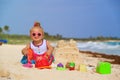 Cute little girl building sandcastle on tropical