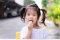 Cute little girl bunches hair and eating oranges into her mouth. Child wore a white shirt sitting in front of the house. Royalty Free Stock Photo