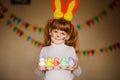 Cute little girl with bunny ears holding bright Easter egg