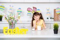 Cute little girl with bunny ears in the kitchen is smiling near the Easter cake Royalty Free Stock Photo