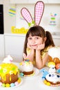 A cute little girl with bunny ears prepares an Easter cake and painted eggs. Religious holiday Royalty Free Stock Photo