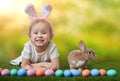 Cute little girl with a bunny rabbit has a easter at green grass background with copy space. Royalty Free Stock Photo