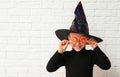 Cute little girl with candies wearing Halloween costume near white brick wall