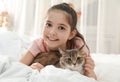 Cute little girl with cat lying on bed. First pet