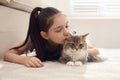 Cute little girl with cat lying on carpet. First pet