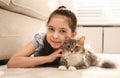 Cute little girl with cat lying on carpet. First pet