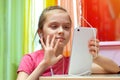 Cute little girl chatting with friends on the Internet using a tablet PC. waving, greeting gesture. Stay at home