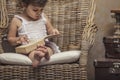 Cute little girl child in a chair, reading a book in interior Royalty Free Stock Photo