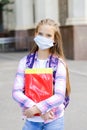 Cute little girl child with face mask with backpack and books. Education concept. Back to school after covid-19.  Preteen student Royalty Free Stock Photo