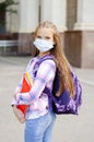 Cute little girl child with face mask with backpack and books. Education concept. Back to school after covid-19.  Preteen student Royalty Free Stock Photo