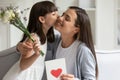 Little daughter congratulate excited young mom presenting flowers Royalty Free Stock Photo