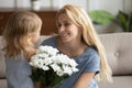 Cute little girl congratulating young mom presenting flowers Royalty Free Stock Photo