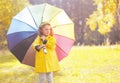 Cute little girl child in yellow jacket with colorful umbrella Royalty Free Stock Photo