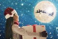 Cute little girl with christmas presents. Santa Claus flying in  moon sky Royalty Free Stock Photo