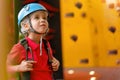 Cute little girl climber in blue protective helmet and gear for climbing standing in climber centre amusement park for children Royalty Free Stock Photo