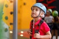 Cute little girl climber in blue protective helmet and gear for climbing standing in climber centre amusement park for children Royalty Free Stock Photo