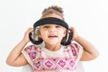 Cute little girl in a colorful dress listening to music with headphones on a white background Royalty Free Stock Photo