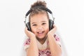 Cute little girl in a colorful dress listening to music with headphones on a white background Royalty Free Stock Photo