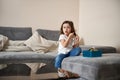 Cute little girl combing her hair with a wooden comb while sitting on the sofa in the living room Royalty Free Stock Photo