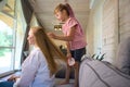 Cute little girl combing long blond hair of her mother Royalty Free Stock Photo