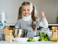 Cute little girl cooking veggies in kitchen