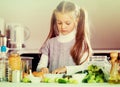 Cute little girl cooking veggies in kitchen