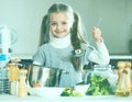 Cute little girl cooking veggies in kitchen