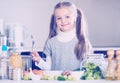 Cute little girl cooking veggies in kitchen