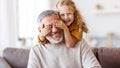 Cute little girl covering eyes with hands of her smiling grandfather while playing together at home Royalty Free Stock Photo