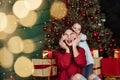 Cute little girl covering her mother eyes. Beautiful room with christmas tree and holiday decoration