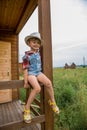 Cute little girl in a cowboy hat,dressed in a denim shorts and red white shirt Royalty Free Stock Photo