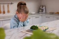 Cute little girl crying and refusing to eat dinner in kitchen
