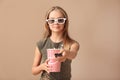 Cute little girl with cup of popcorn switching channels on color background Royalty Free Stock Photo