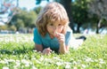 Cute little girl on the daisy flowers meadow in spring day. Happy childhood. Boy lying on grass. Cute kid child enjoying Royalty Free Stock Photo