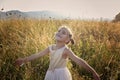 Cute girl dancing through a beautiful meadow with wheat and flowers in the mountains Royalty Free Stock Photo