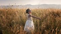 Cute girl dancing through a beautiful meadow with wheat and flowers in the mountains Royalty Free Stock Photo