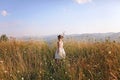 Cute girl dancing through a beautiful meadow with wheat and flowers in the mountains Royalty Free Stock Photo