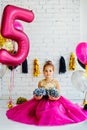 Cute little girl with dark hair, in a beautiful holiday dress and pink balloons for her birthday. The child is 5 years old Royalty Free Stock Photo