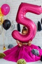 Cute little girl with dark hair, in a fancy dress and balloons for her birthday. Child 5 years old Royalty Free Stock Photo