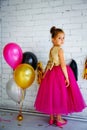 Cute little girl with dark hair, in a fancy dress and balloons for her birthday. Child 5 years old Royalty Free Stock Photo