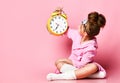 Yawning teenage girl holding an alarm clock while sitting in a housecoat on the floor. Royalty Free Stock Photo