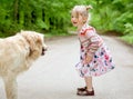 Cute little girl with a dog, smiling, standing on the forest road. Child friendship with dogs Royalty Free Stock Photo